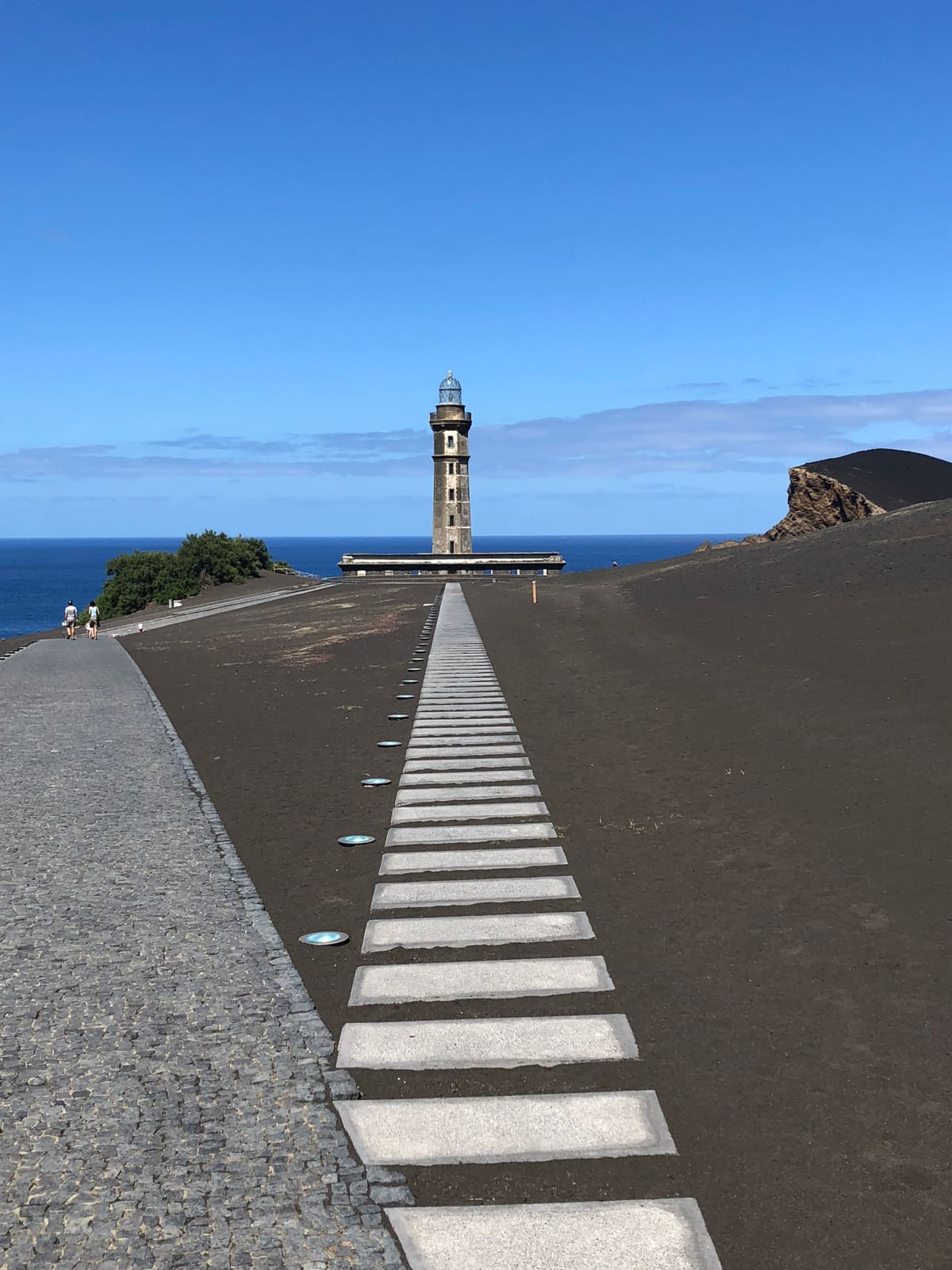 Capelinhos lighthouse and volcanic landscape under a blue sky
