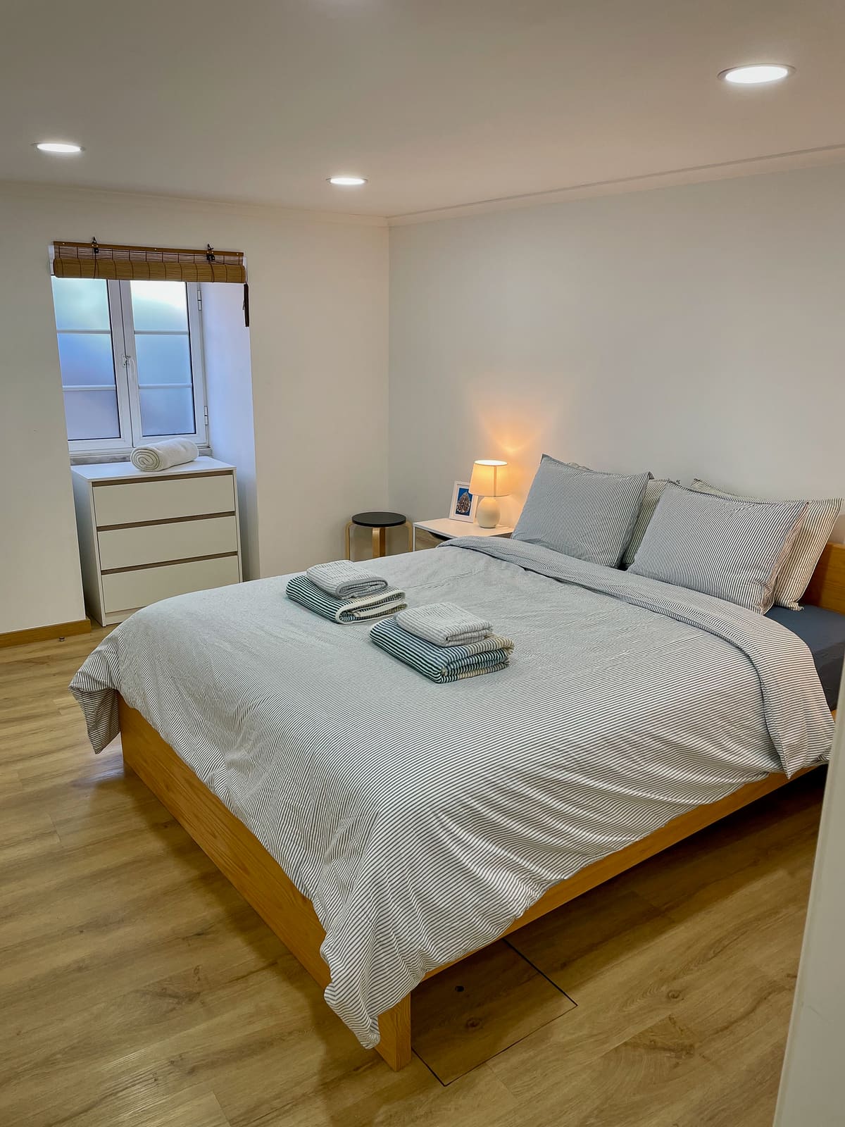 Second bedroom at Casa Tarapacana with a made-up bed and bedside lamp at dusk